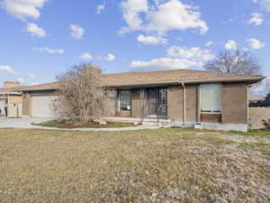 Single story home with a garage and a front lawn