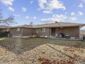 Rear view of house with a lawn, central air condition unit, and a patio