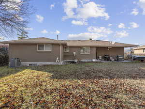 Back of property with a lawn, a patio area, and central AC