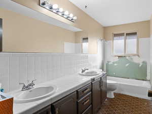 Full bathroom featuring washtub / shower combination, vanity, toilet, and backsplash