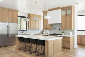 Kitchen with stove, light wood-type flooring, stainless steel built in refrigerator, a kitchen island, and hanging light fixtures