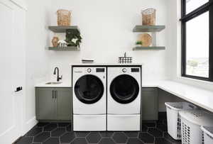 Clothes washing area featuring washer and clothes dryer, cabinets, sink, and a wealth of natural light