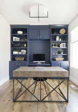 Home office featuring built in shelves and light wood-type flooring