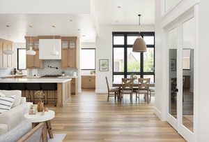 Kitchen with tasteful backsplash, light hardwood / wood-style flooring, pendant lighting, a breakfast bar area, and a kitchen island