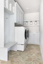 Clothes washing area featuring cabinets and washing machine and dryer