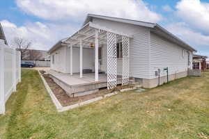 Rear view of house featuring a lawn, a pergola, and a wooden deck