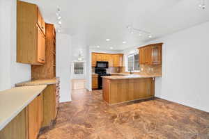 Kitchen with kitchen peninsula, sink, backsplash, and black appliances