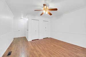 Main bedroom featuring wood-style floors, ceiling fan, and multiple closets