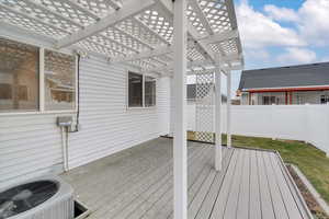 Wooden deck with a pergola and central air condition unit