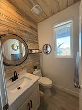 Bathroom featuring wood ceiling, vanity, wood-type flooring, toilet, and wood walls