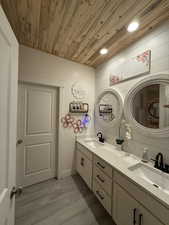 Bathroom featuring hardwood / wood-style floors, vanity, wooden ceiling, and wood walls