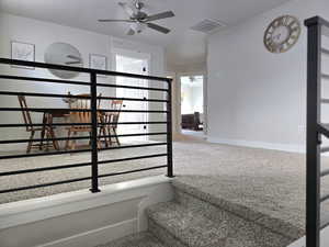 Stairs featuring carpet floors, ceiling fan, and a healthy amount of sunlight