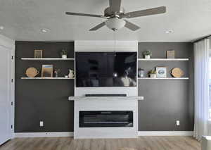 Unfurnished living room featuring a large fireplace, a textured ceiling, and light hardwood / wood-style flooring