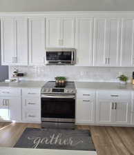 Kitchen featuring light hardwood / wood-style flooring, white cabinets, and appliances with stainless steel finishes