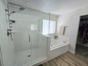 Bathroom featuring plus walk in shower, wood-type flooring, and a textured ceiling