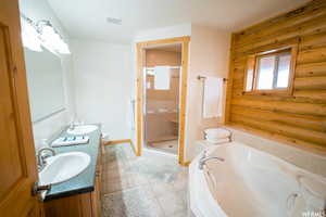 Full bathroom with tile patterned floors, vanity, separate shower and tub, log walls, and toilet