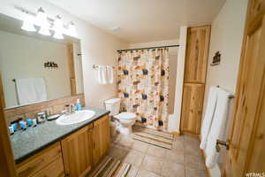 Full bathroom featuring tasteful backsplash, tile patterned floors, vanity, shower / bathtub combination with curtain, and toilet