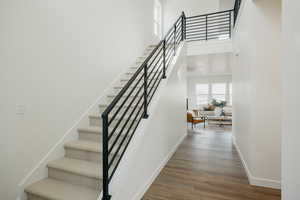 Stairway featuring a towering ceiling and hardwood / wood-style floors