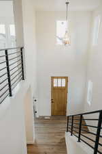 Foyer entrance featuring hardwood / wood-style floors, a towering ceiling, a chandelier, and a healthy amount of sunlight