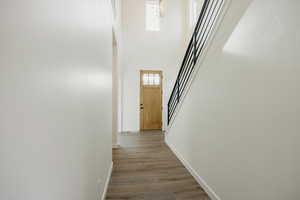 Corridor featuring a towering ceiling, wood-type flooring, a chandelier, and a healthy amount of sunlight