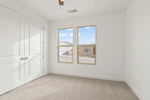 Unfurnished bedroom featuring light carpet, a closet, and ceiling fan