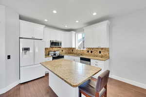 Kitchen featuring appliances with stainless steel finishes, tasteful backsplash, sink, white cabinets, and a center island