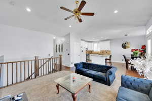 Living room with light hardwood / wood-style floors, ceiling fan, and lofted ceiling