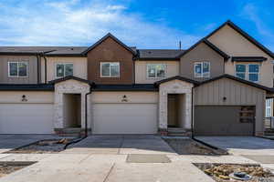 Multi unit property with stucco siding, a garage, concrete driveway, and stone siding