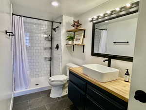 Bathroom with tile patterned floors, a shower with curtain, vanity, and toilet