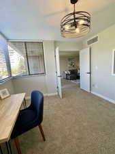 Home office with carpet floors, a textured ceiling, and a chandelier