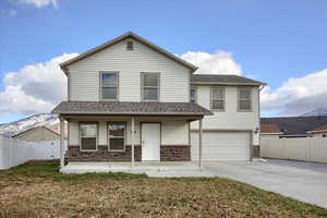 Front of property featuring covered porch, a mountain view, a garage, and a front yard