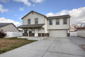 View of front of home with covered porch, a mountain view, a garage, and a front lawn