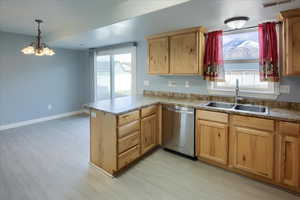 Kitchen with kitchen peninsula, sink, pendant lighting, an inviting chandelier, and dishwasher