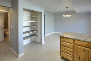 Interior space featuring light wood-type flooring, decorative light fixtures, and pantry