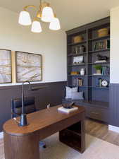 Home office featuring built in features, light wood-type flooring, and an inviting chandelier