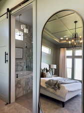 Bedroom with a barn door and a notable chandelier