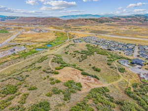 Aerial view of property and surrounding area featuring a water and mountain view, rural landscape, and nearby suburban area