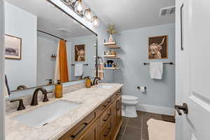 Bathroom featuring tile patterned flooring, vanity, a textured ceiling, and toilet