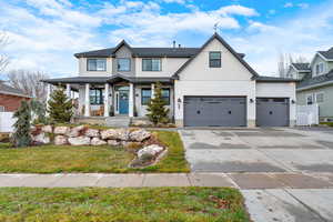 View of front of property with a front lawn, covered porch, and a garage