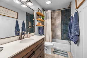 Full bathroom with vanity, shower / bathtub combination with curtain, and toilet