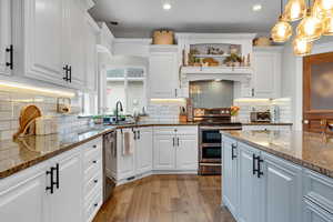 Kitchen with white cabinets, pendant lighting, and appliances with stainless steel finishes