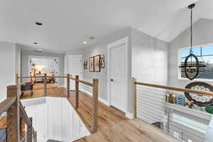 Kitchen with decorative light fixtures, vaulted ceiling, and light hardwood / wood-style flooring