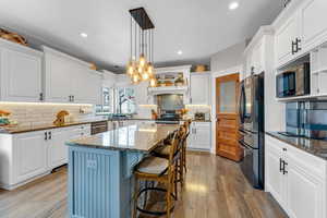 Kitchen featuring a center island, white cabinetry, dark stone countertops, and black appliances