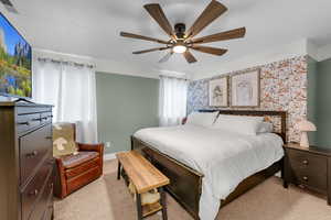 Bedroom featuring a textured ceiling, light colored carpet, and ceiling fan