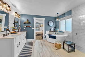 Bathroom with vanity, ceiling fan, a textured ceiling, and plus walk in shower