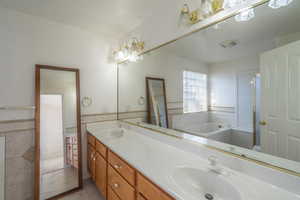 Bathroom with tile patterned flooring, a washtub, tile walls, and vanity