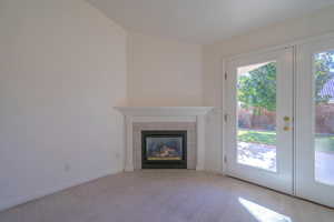 Unfurnished living room with light colored carpet, a fireplace, and french doors