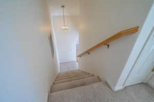 Staircase featuring carpet flooring and a chandelier