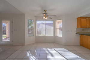 Unfurnished dining area with ceiling fan and light tile patterned flooring