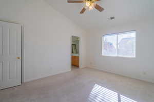 Carpeted spare room featuring ceiling fan and high vaulted ceiling